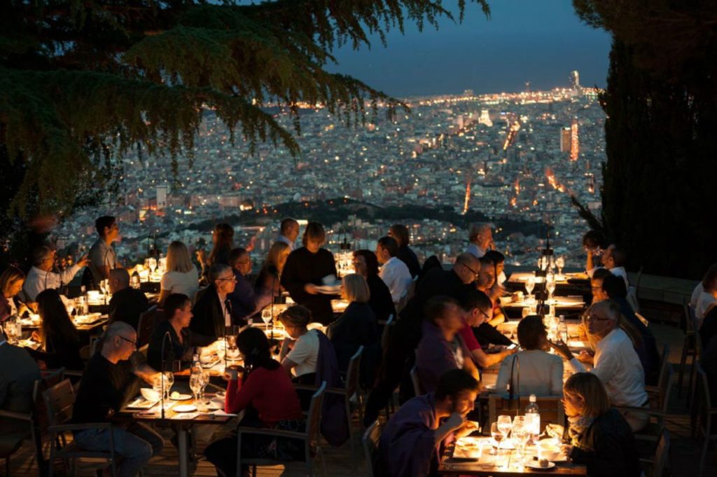 Personas cenando en el mirador del observatorio Fabra con la ciudad de fondo