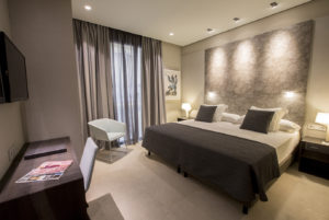 habitación de hotel minimalista de colores oscuros con cama grande y zona de trabajo