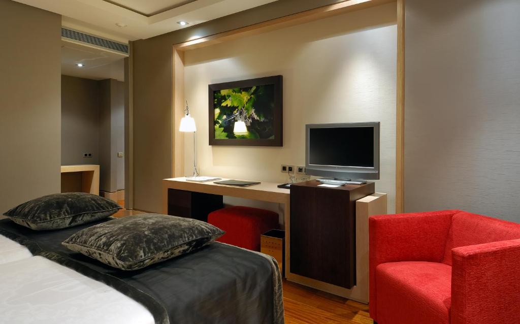 habitación de hotel de tonos oscuros con cama, espacio de trabajo y sillón