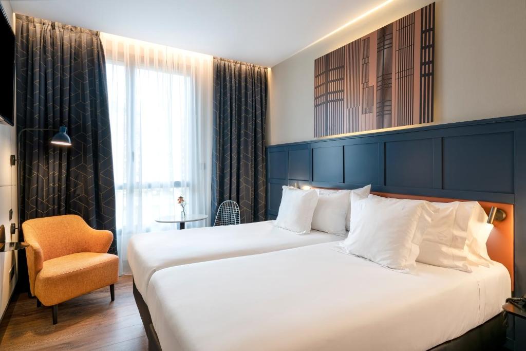 Habitación con dos camas, butaca y ventana grande en Vincci Consulado de Bilbao