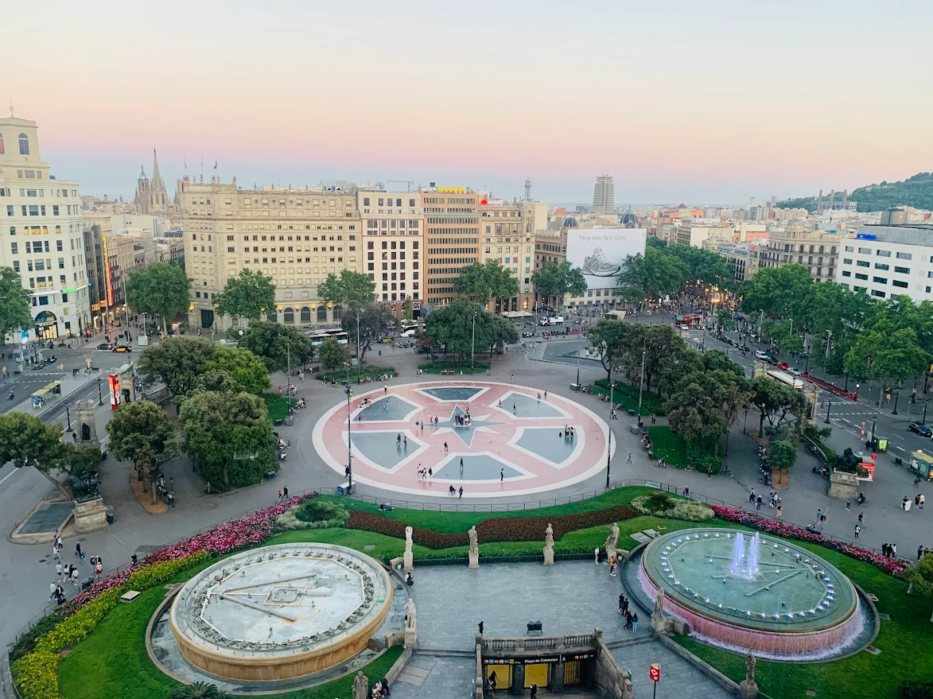 Aerial view of Plaça Catalunya. From here you can see the central circle and two round fountains, one of them lit up.