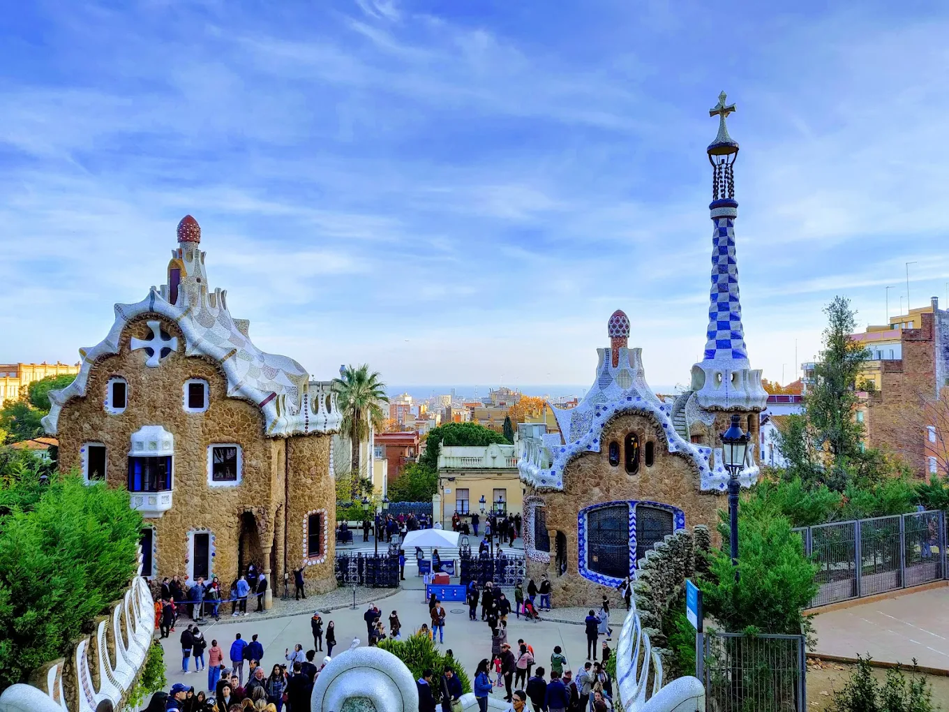 The two typical houses of Parc Güell, with brown stone walls and white and blue roofs.