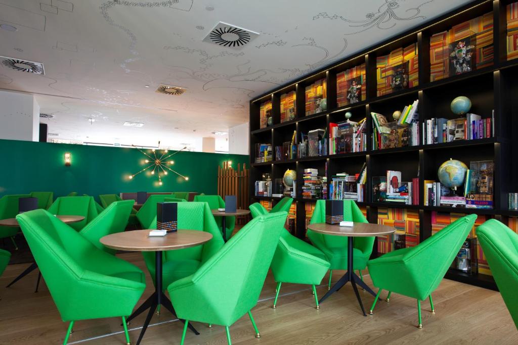 zona de cafetería con butacadas verdes modernas y estanterías de libros