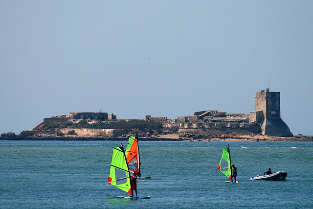 Castillo de Sancti Petri con gente haciendo Windsurf