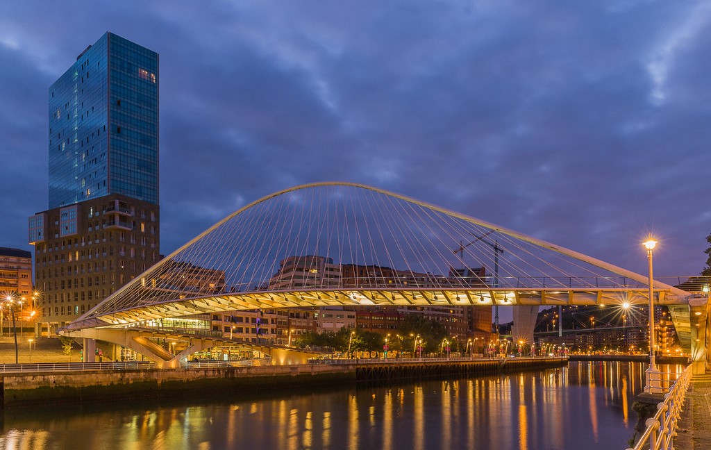 Vista nocturna del puente Zubizuri iluminado frente al cielo nocturno