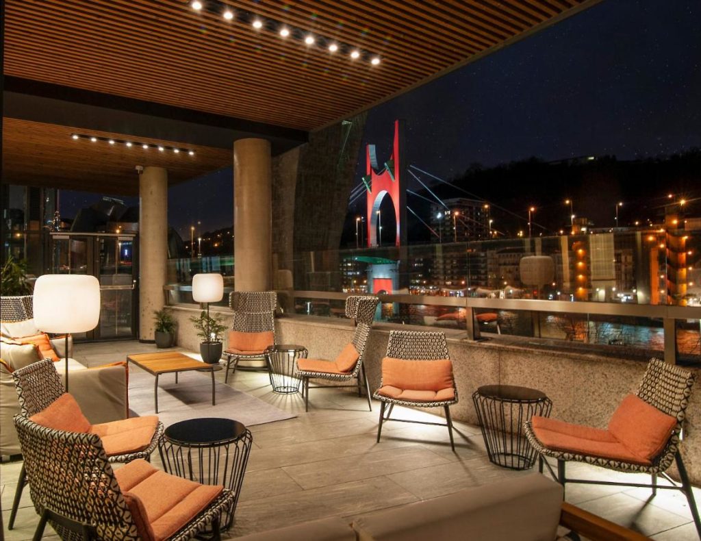 terraza con sillas y mesillas modernas y vistas a la ciudad por la noche