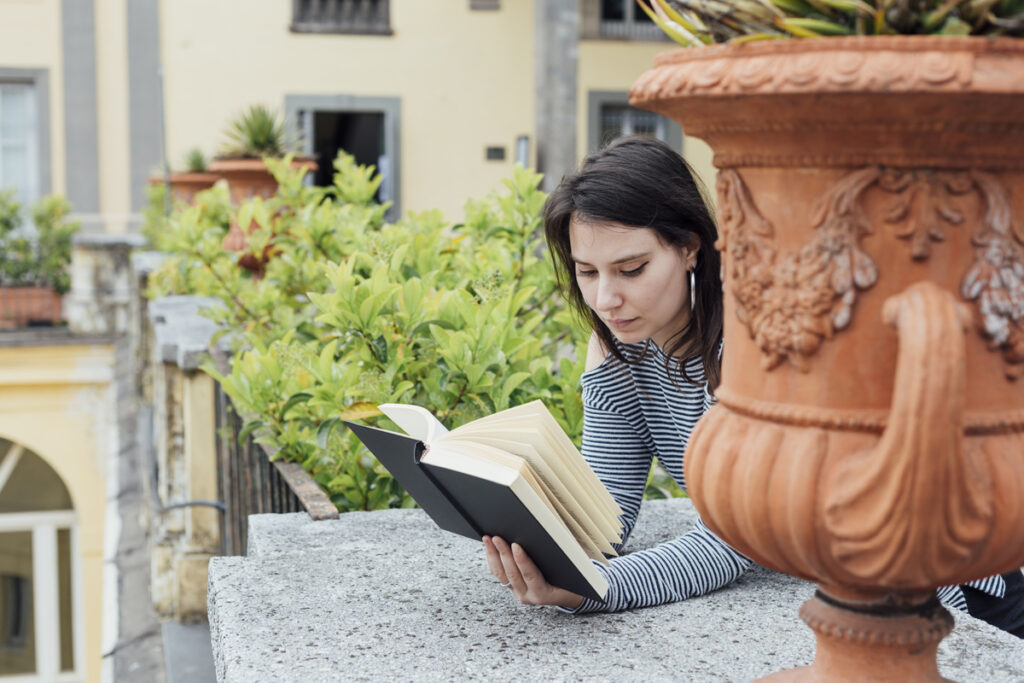 ciudades literarias. Chica joven leyendo un libro en la calle